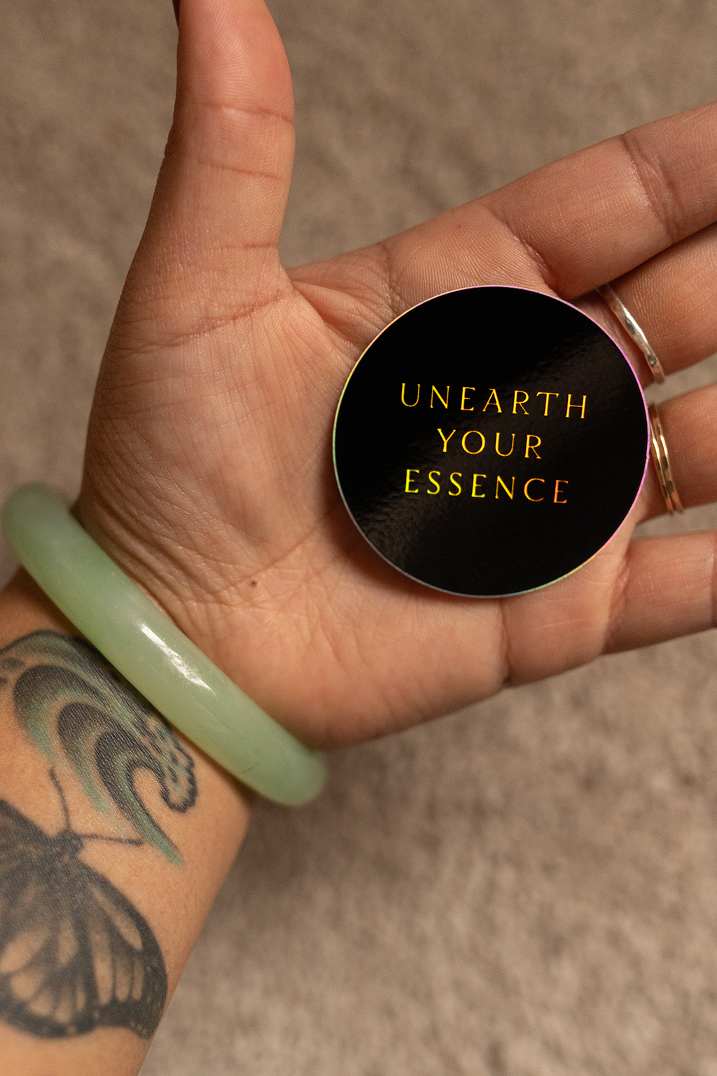 Hand holding round sticker, wearing a jade bracelet